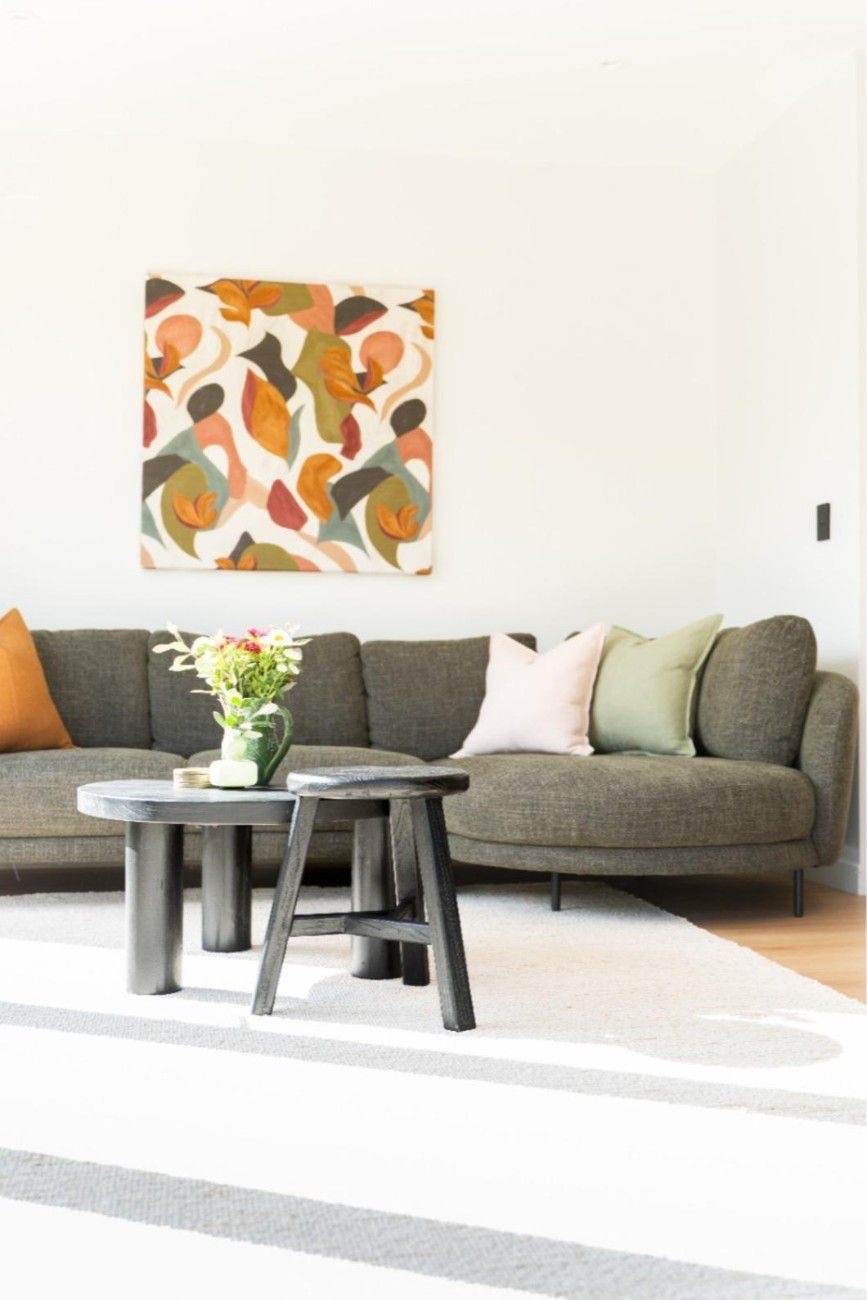 A finished living room with a grey sofa, round coffee tables and abstract artwork