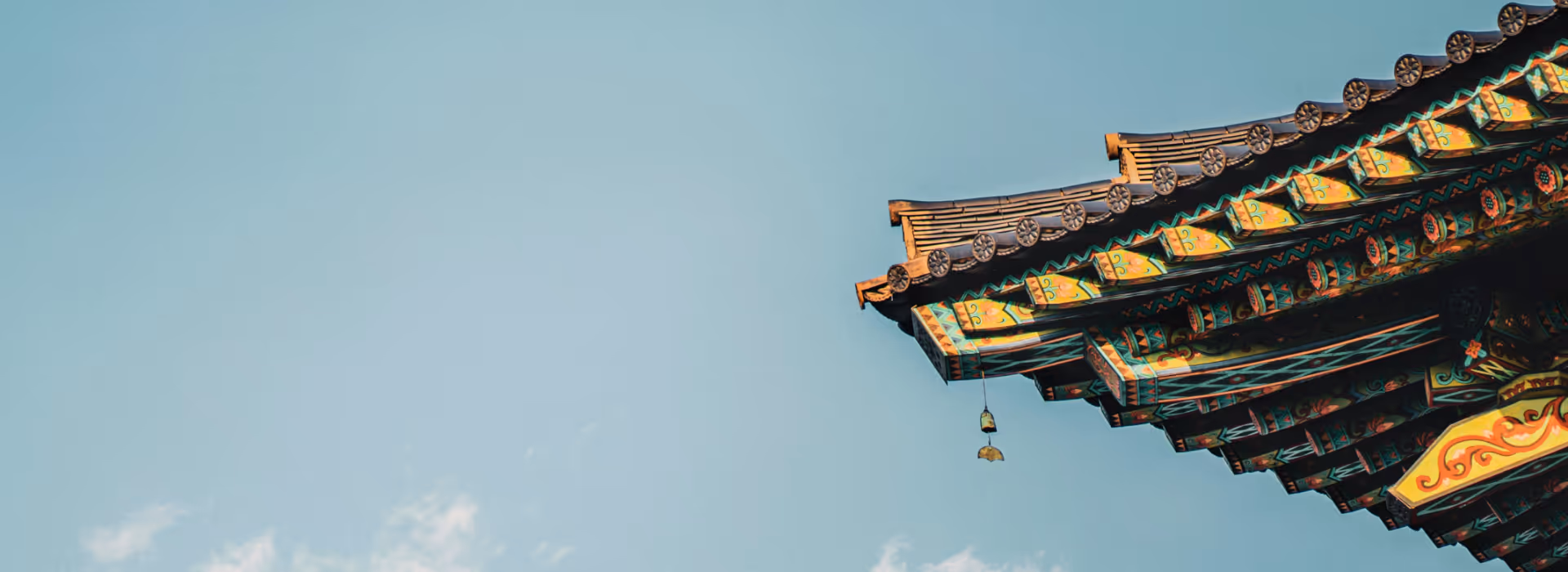 Avant-toit décoré d’un temple traditionnel coréen, orné de motifs dancheong multicolores sous un ciel bleu