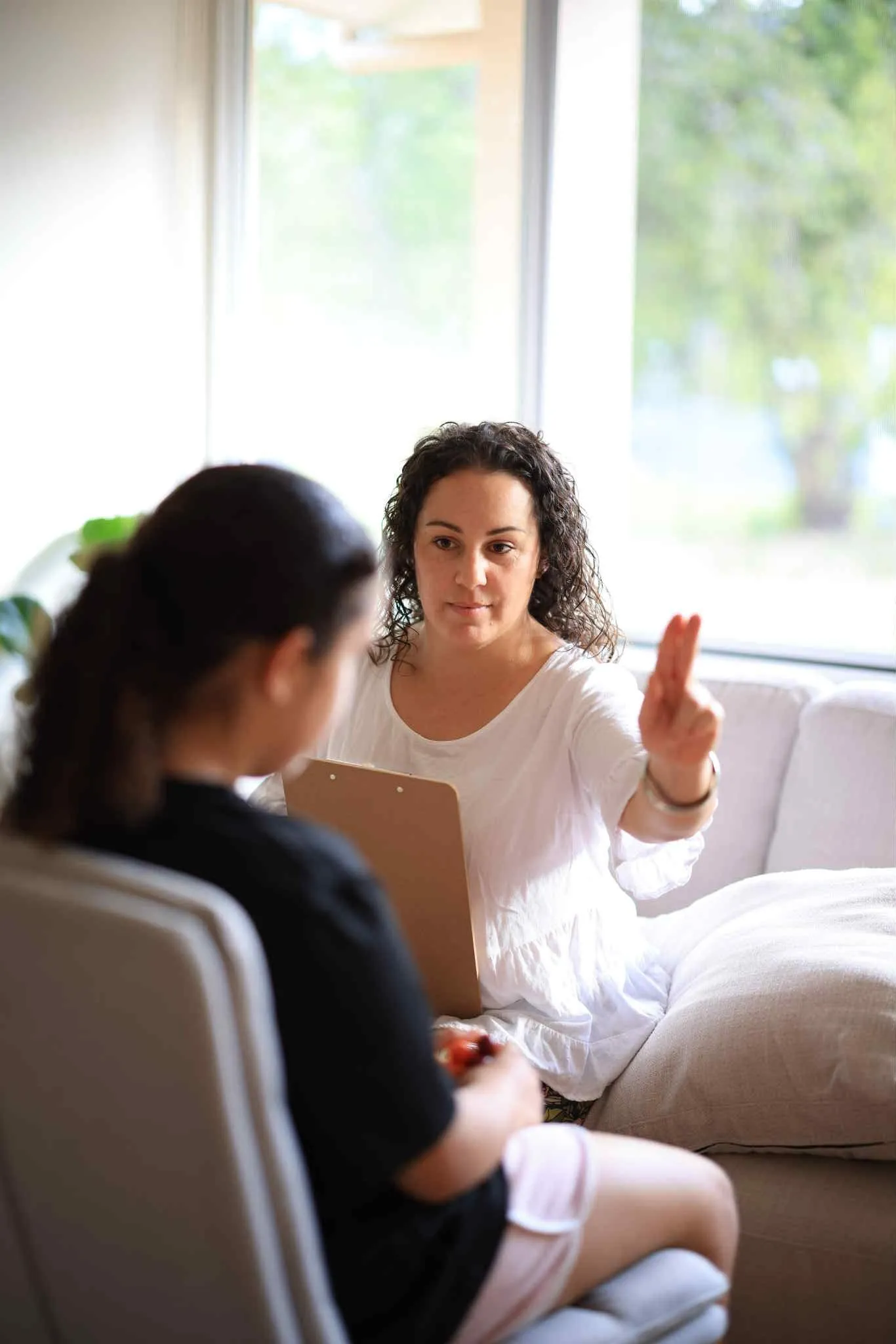 A woman sitting on a couch talking to another woman.