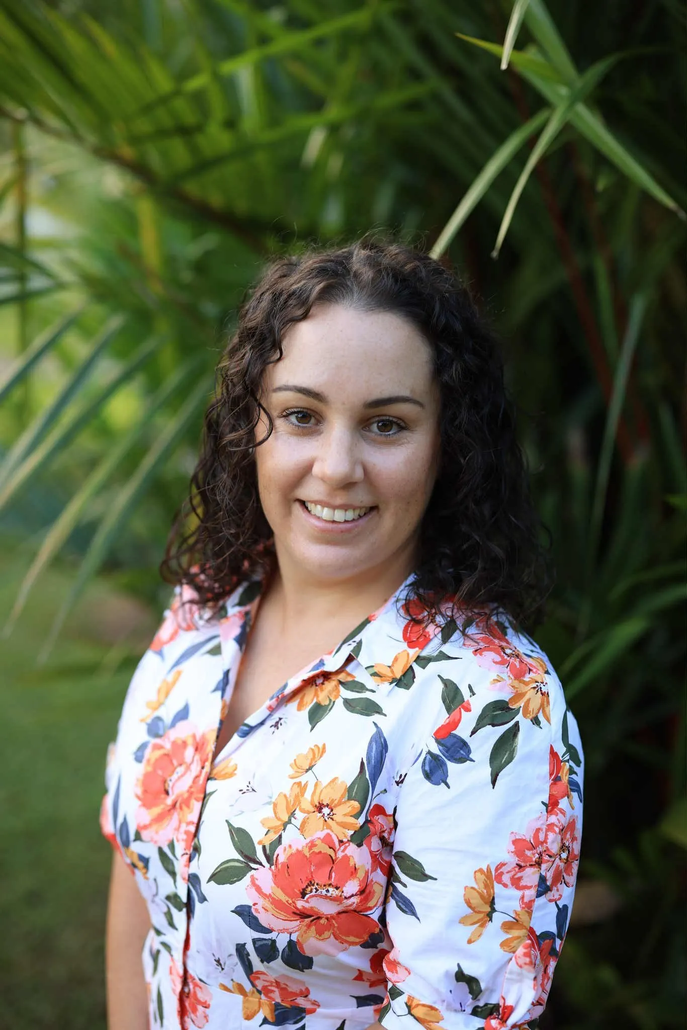 Jakara in a floral shirt standing in front of a palm tree.