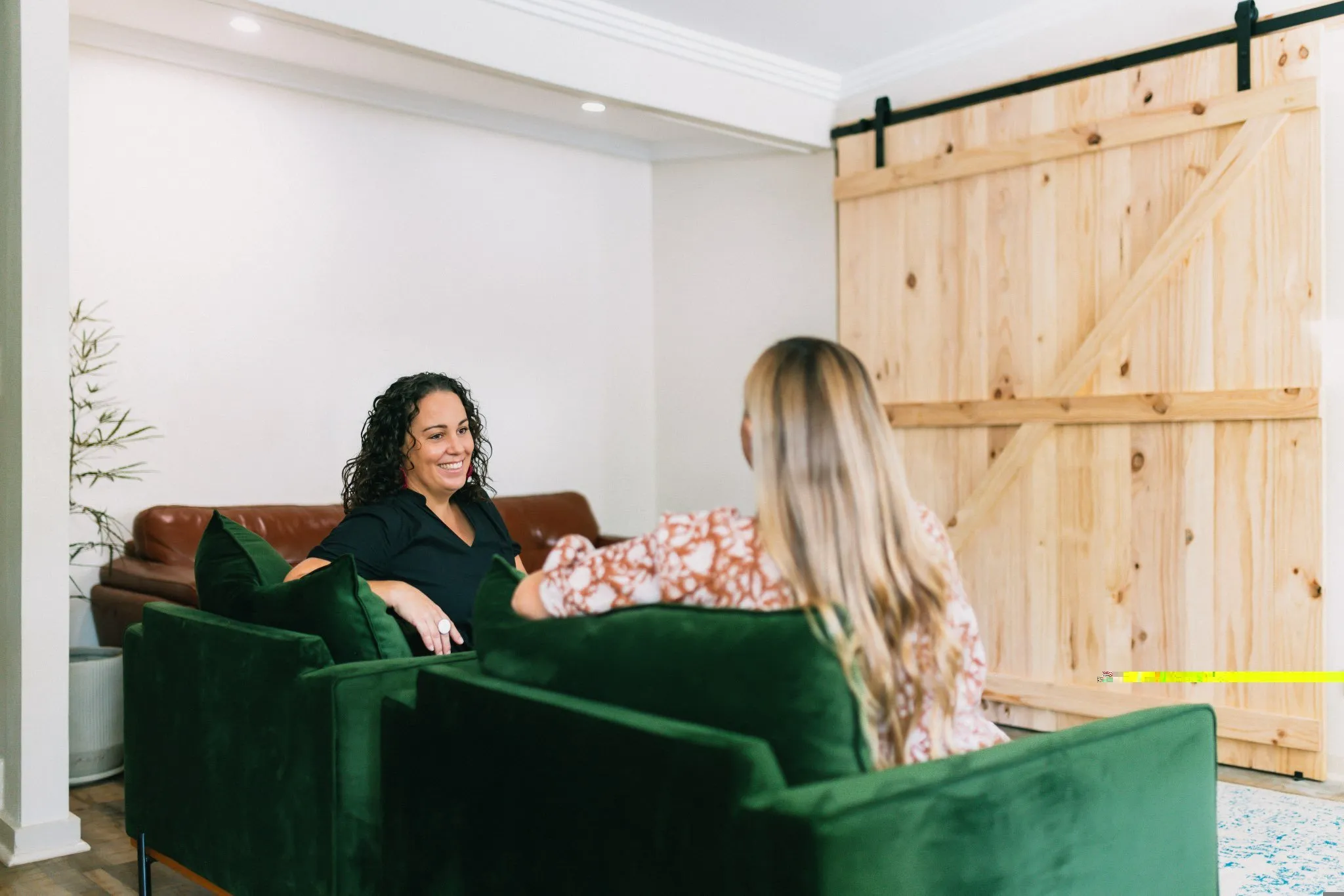 A woman sitting on a couch talking to another woman.