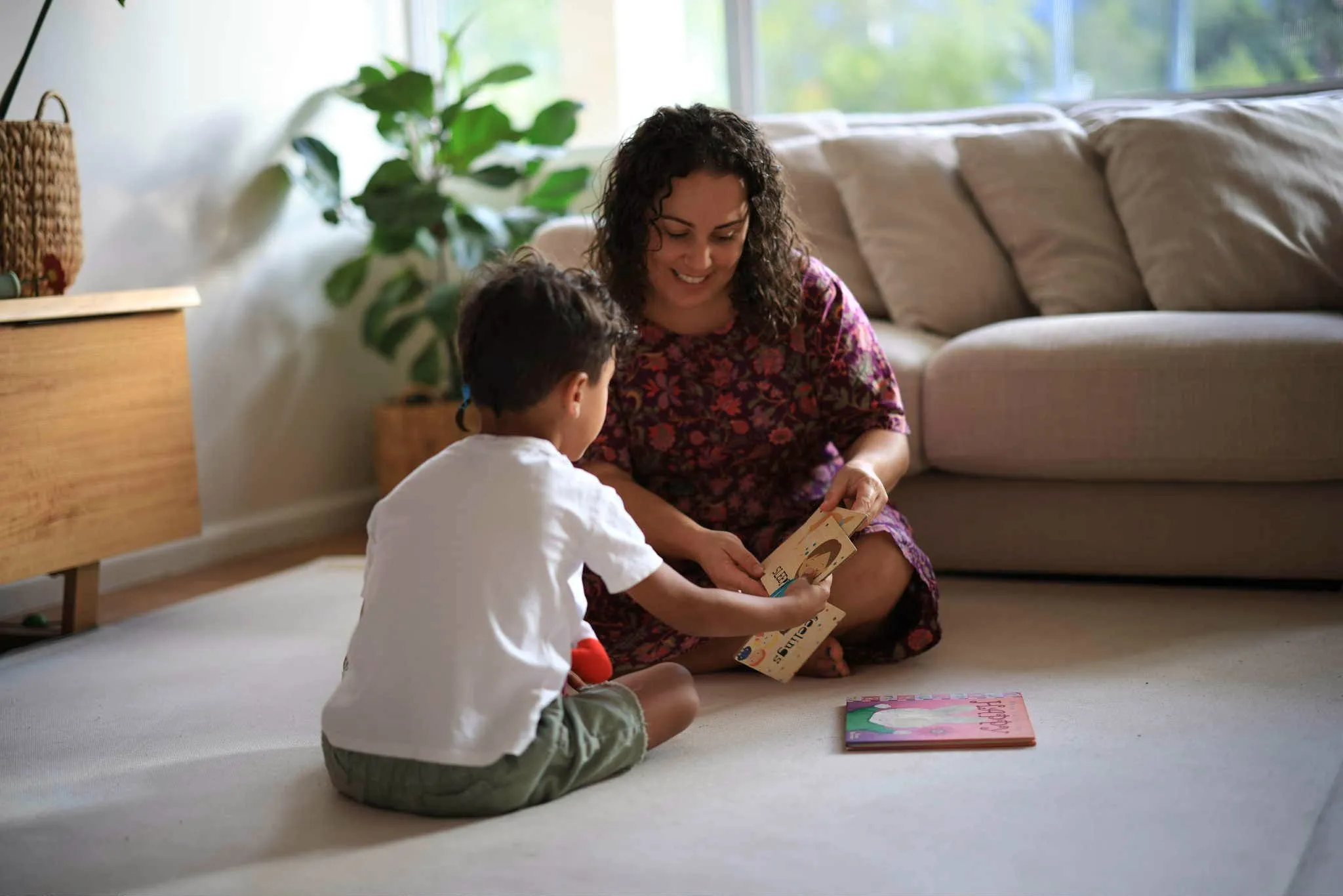 A woman sitting on the floor playing with a child.