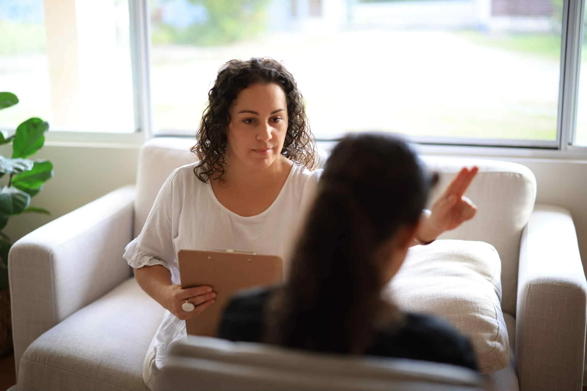 A woman sitting on a couch talking to another woman.