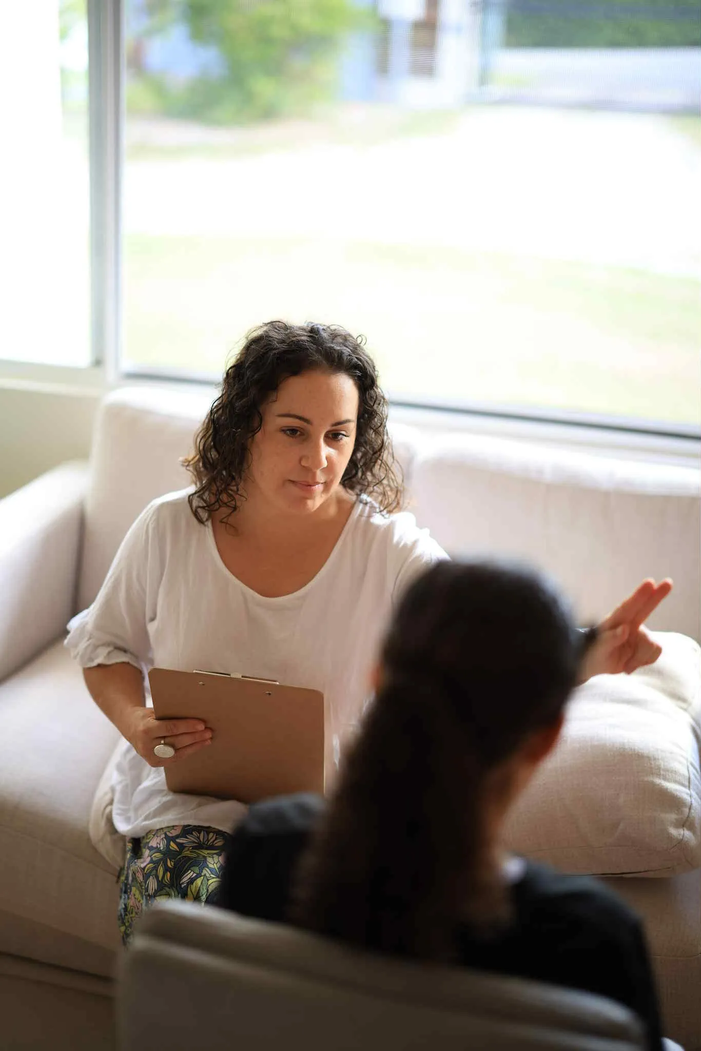 A woman sitting on a couch talking to another woman.