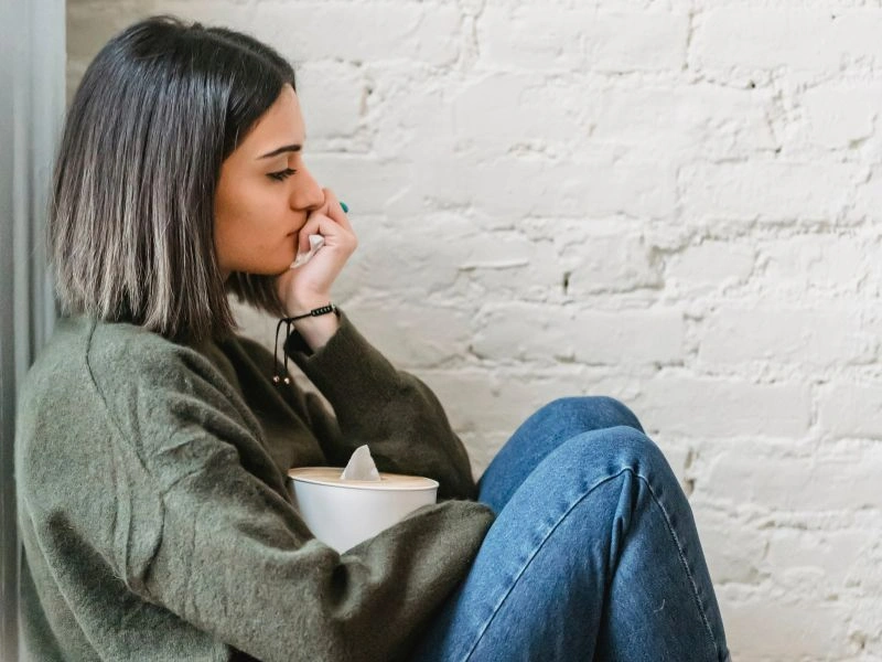 A woman sitting on the floor with a cup of coffee.