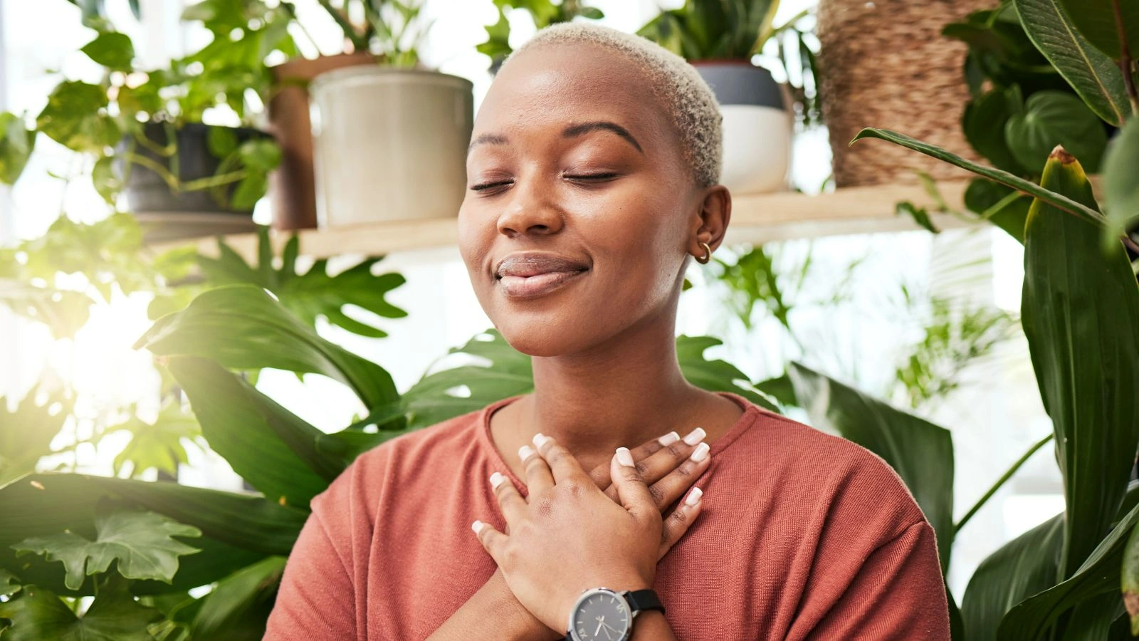 A woman smiling while her hands are on her chest and her eyes closed