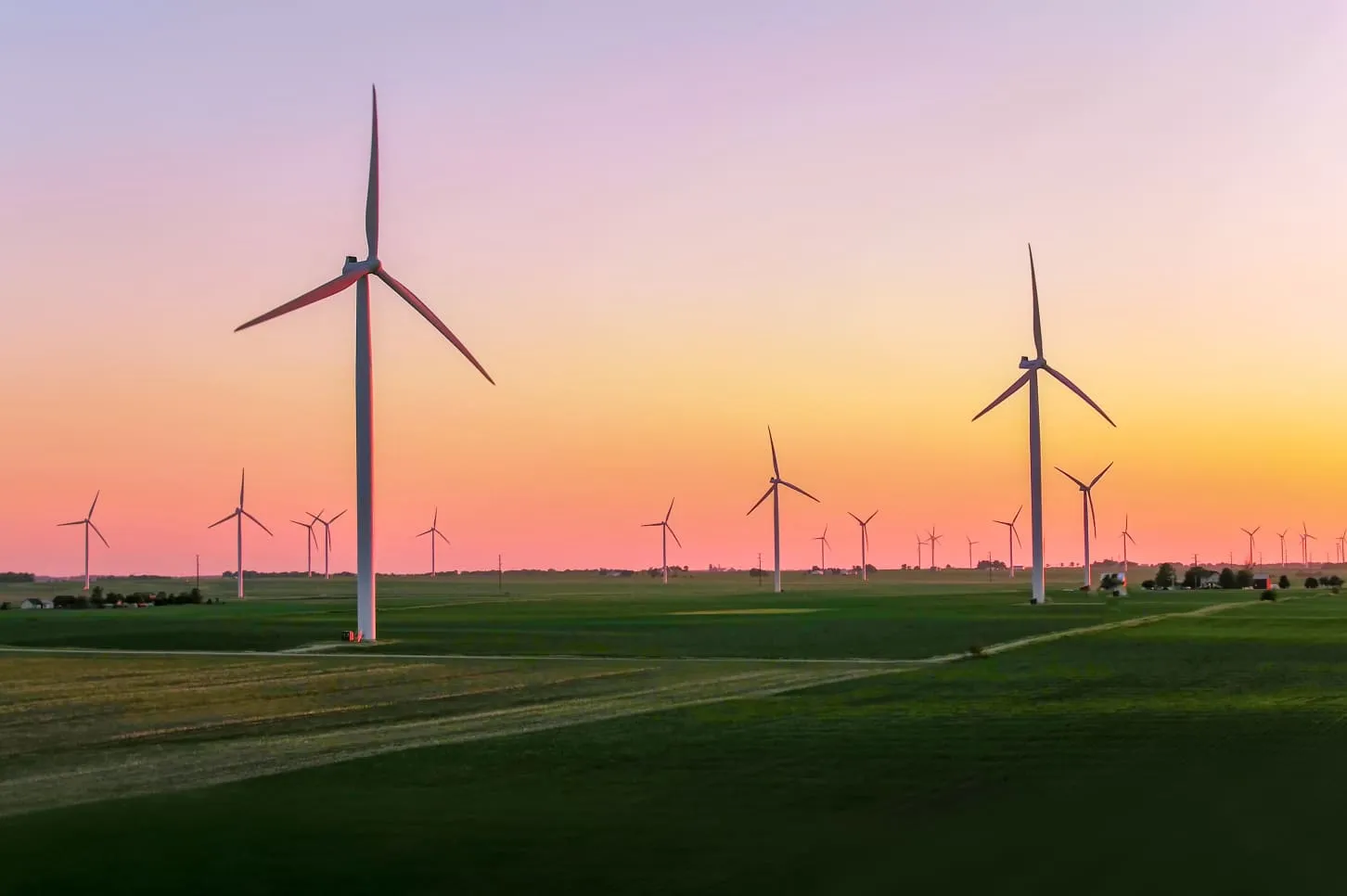 A group of windmills in a field at sunset.