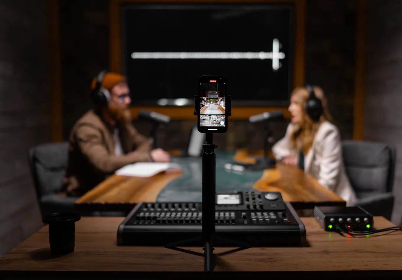 Two people sitting at a table with headphones on.