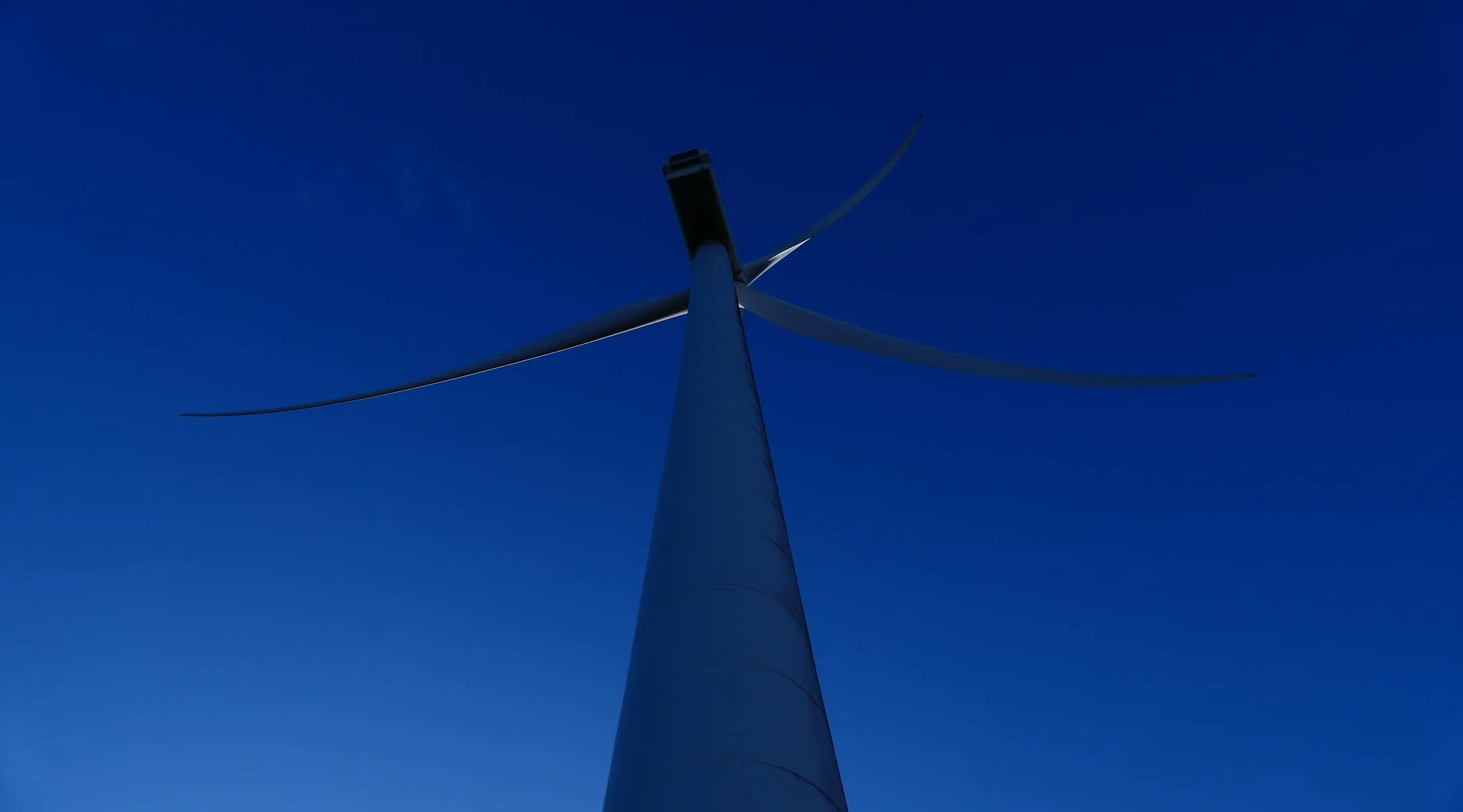 A wind turbine with a blue sky in the background.