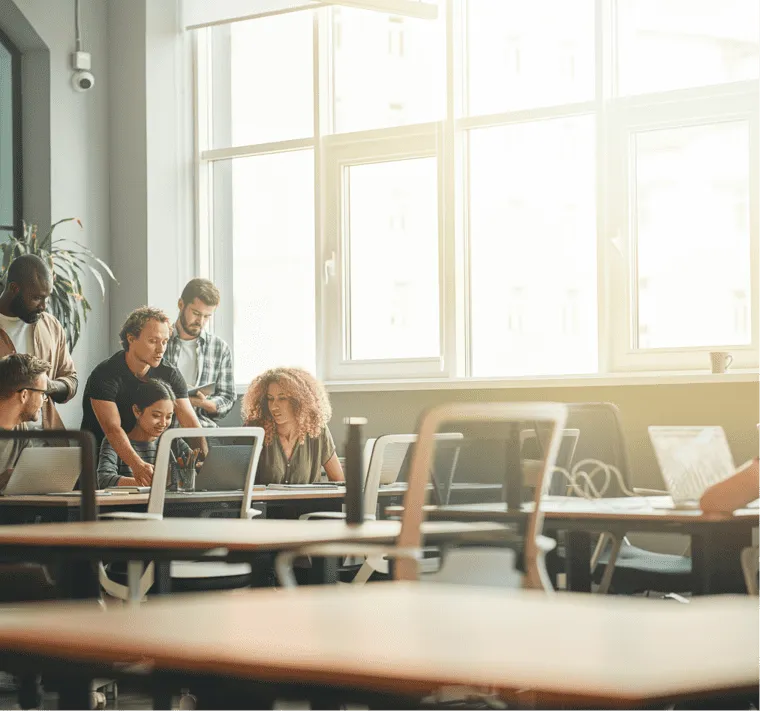 A group of people working on laptops in a classroom.