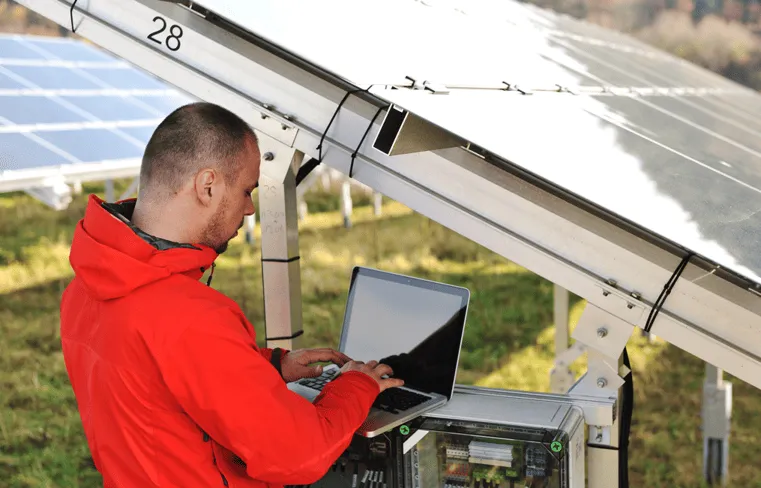 A man in a red jacket working on a laptop.