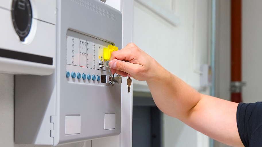 Elektroniker der mit einem Schlüssel eine Anlage scharf schaltet