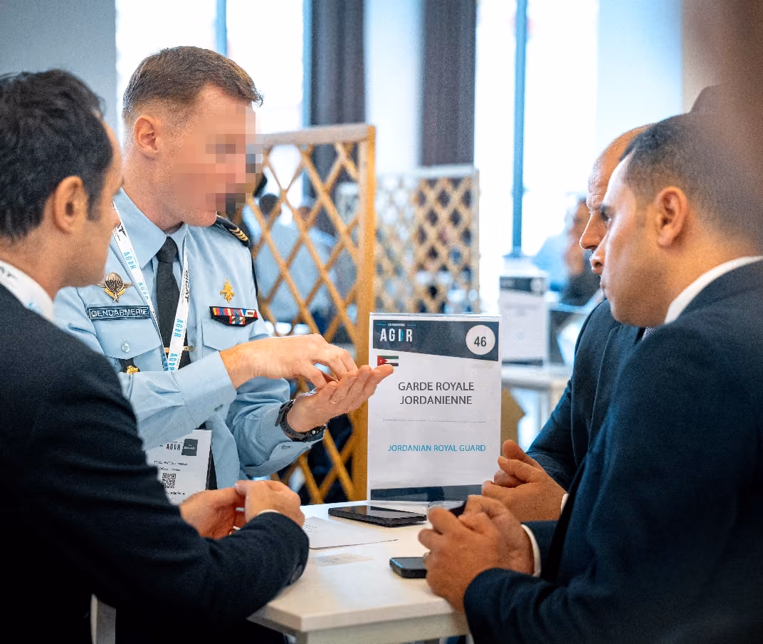 Quatre hommes discutent autour d'une table avec un panneau indiquant Garde Royale Jordanienne.