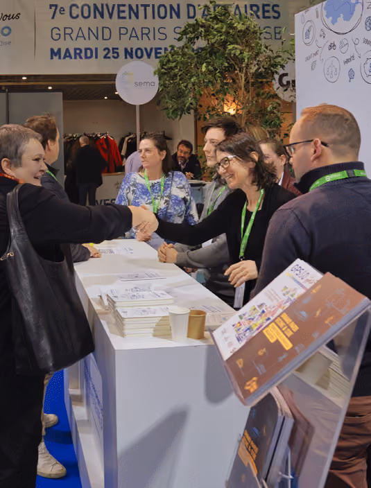 Personnes se serrant la main et discutant sur un stand lors de la 7e Convention d'aires du Grand Paris.