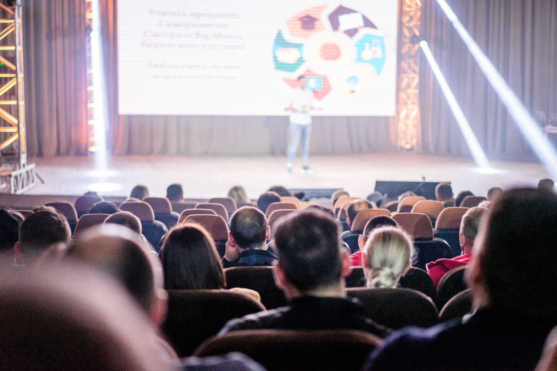 Audience attentively watching a presentation in a conference setting, with stage lights and speaker visible — Preventive Medicine