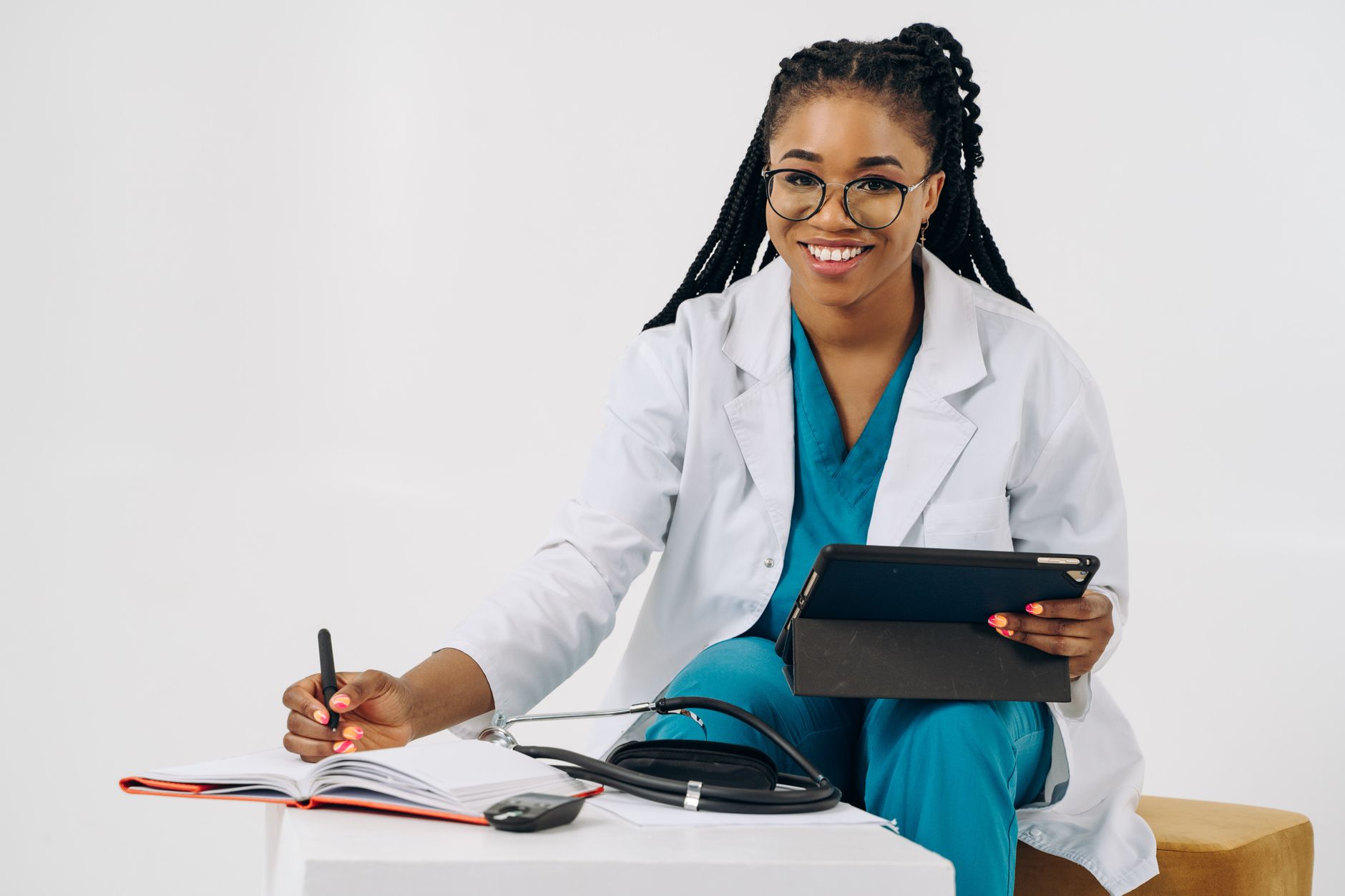 Smiling female doctor in scrubs with tablet and stethoscope, writing notes — AI & Digital Health