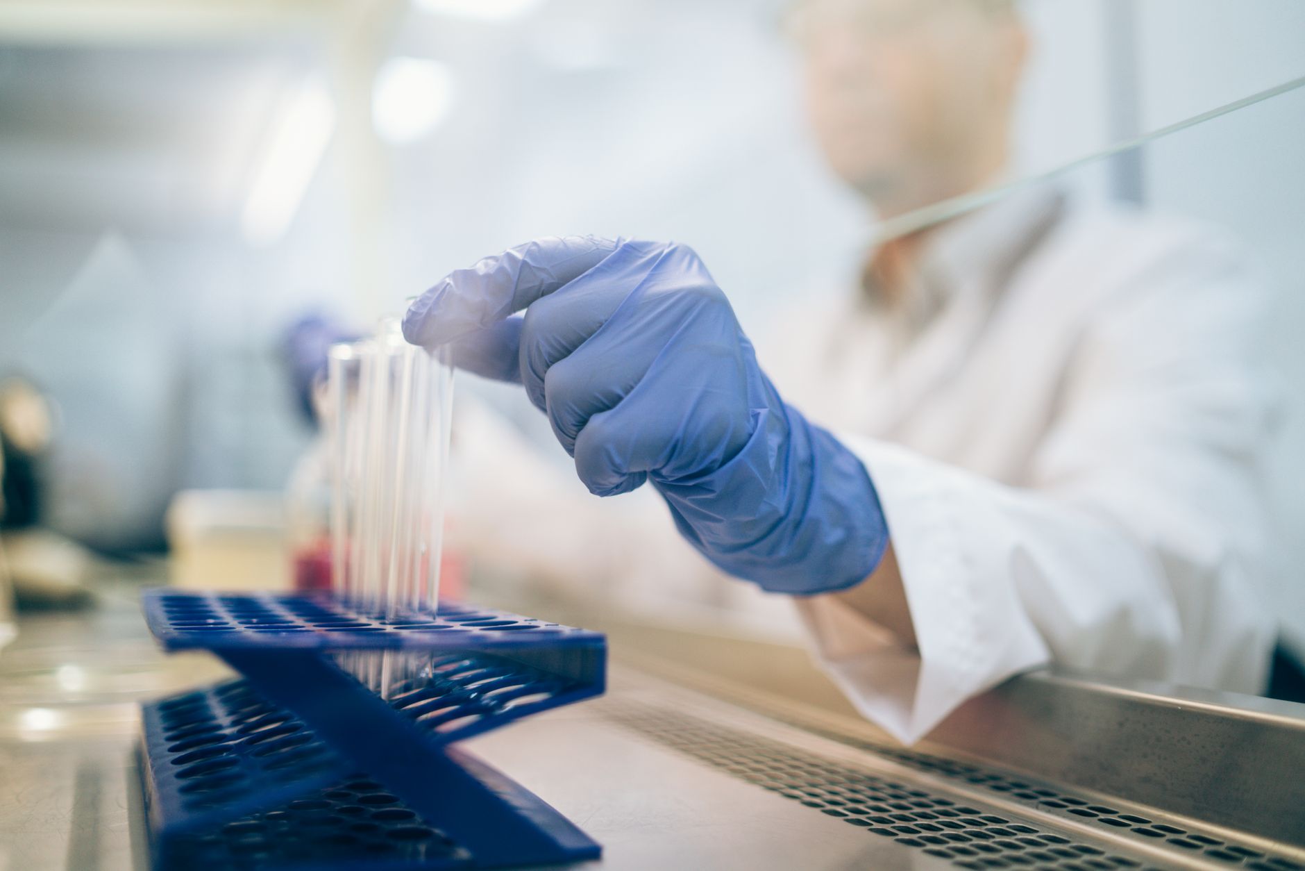 Close-up of a scientist wearing gloves and handling test tubes in a laboratory environment — Regenerative Medicine