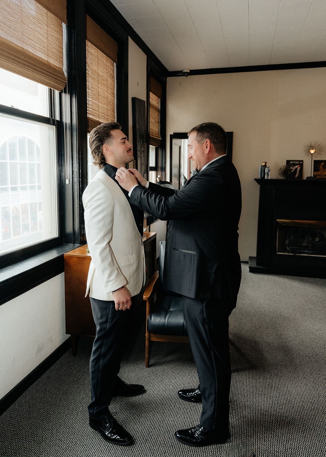 Father helping groom adjust his tie in a downtown York wedding getting ready suite before the ceremony.