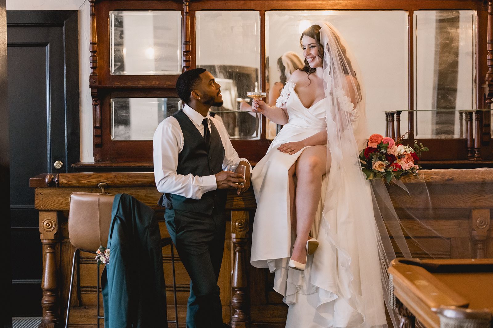 Bride and groom sharing a toast at the original wooden bar inside The Speakeasy wedding getting ready suite in downtown York, PA.
