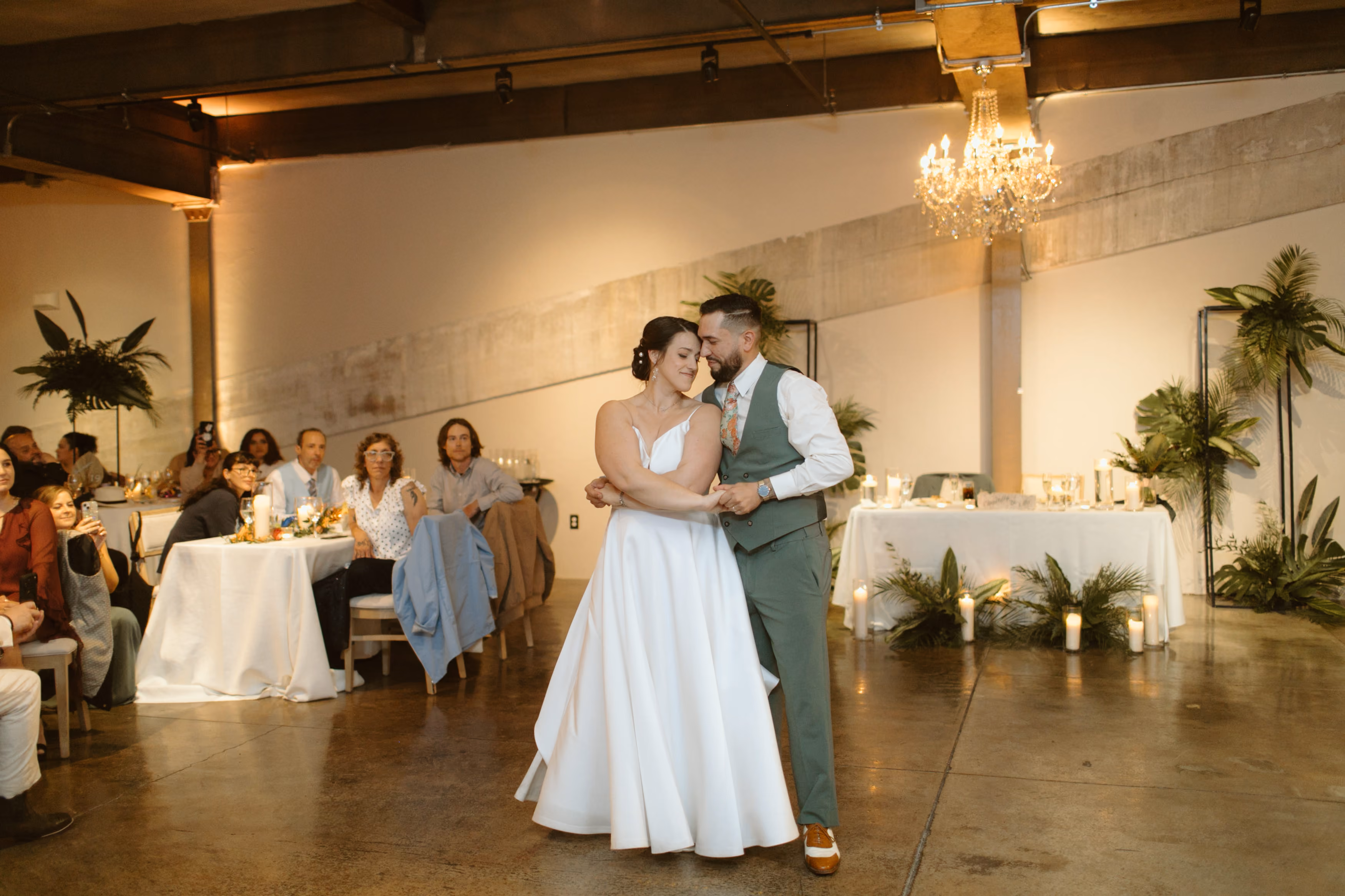 Bride and groom sharing their first dance during their wedding reception inside The Bond's industrial wedding venue with crystal chandeliers in downtown York, Pennsylvania.