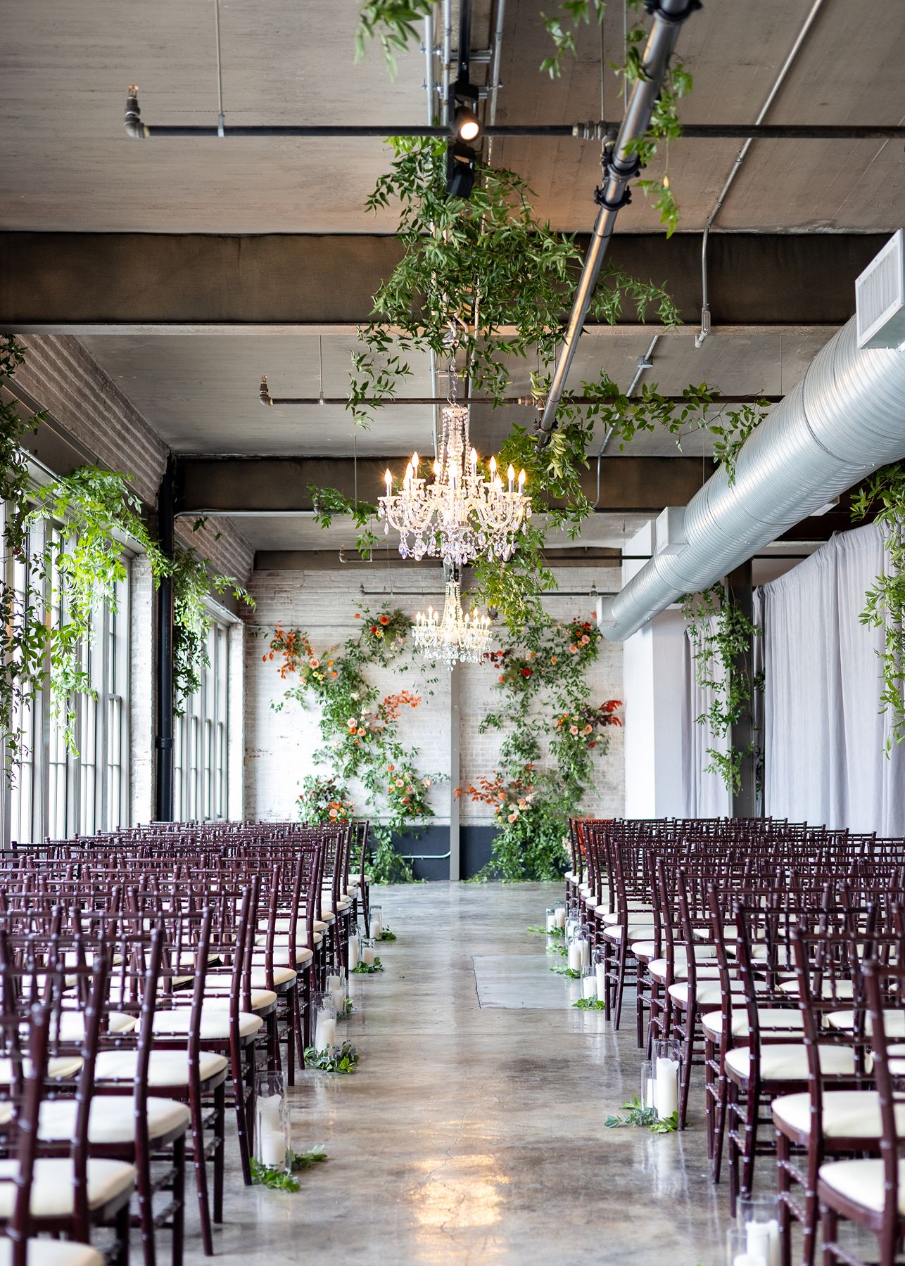Romantic garden-inspired wedding ceremony featuring lush floral installations and crystal chandeliers inside The Bond wedding venue in downtown York, PA.
