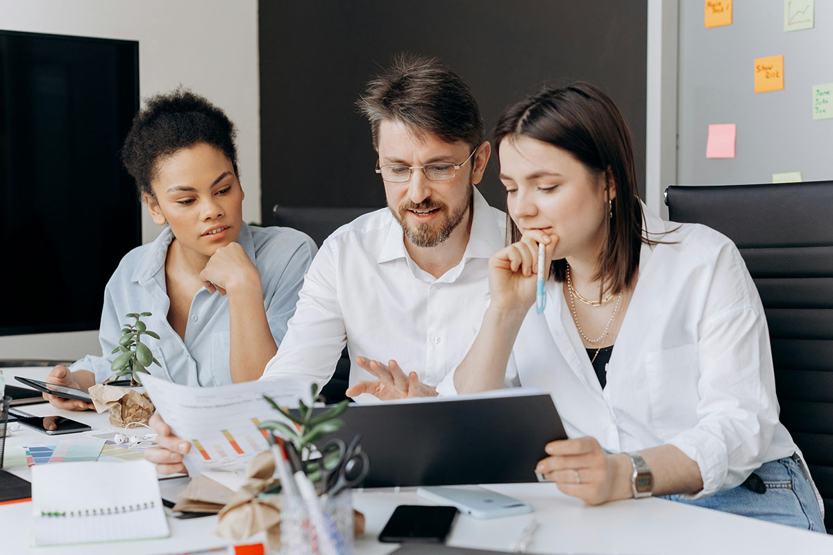 Un groupe de personnes assises autour d'une table travaillant pour Simpleez by Pragmatism IT