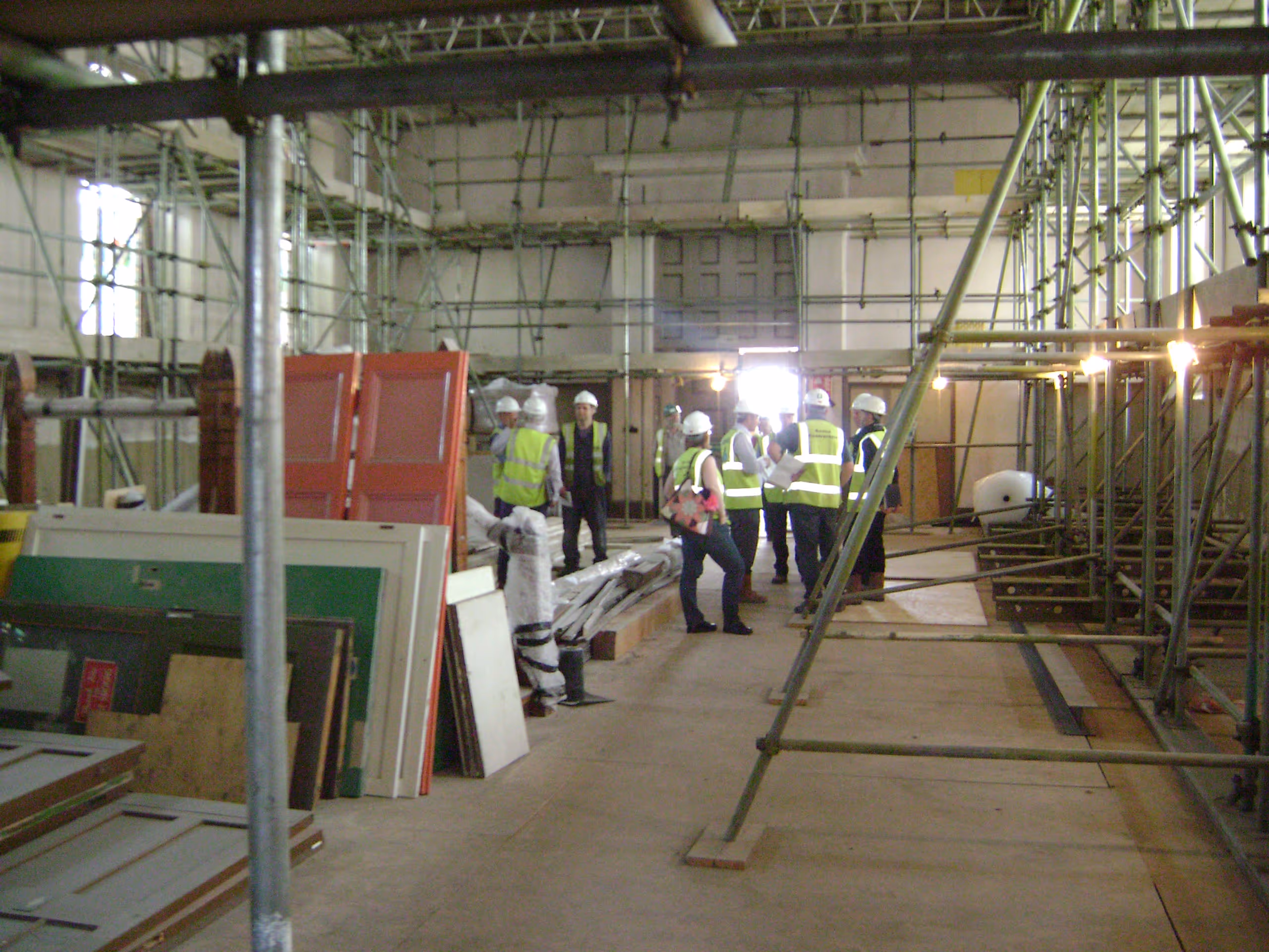 Construction workers in hard hats and high-vis vests inside building during renovation work