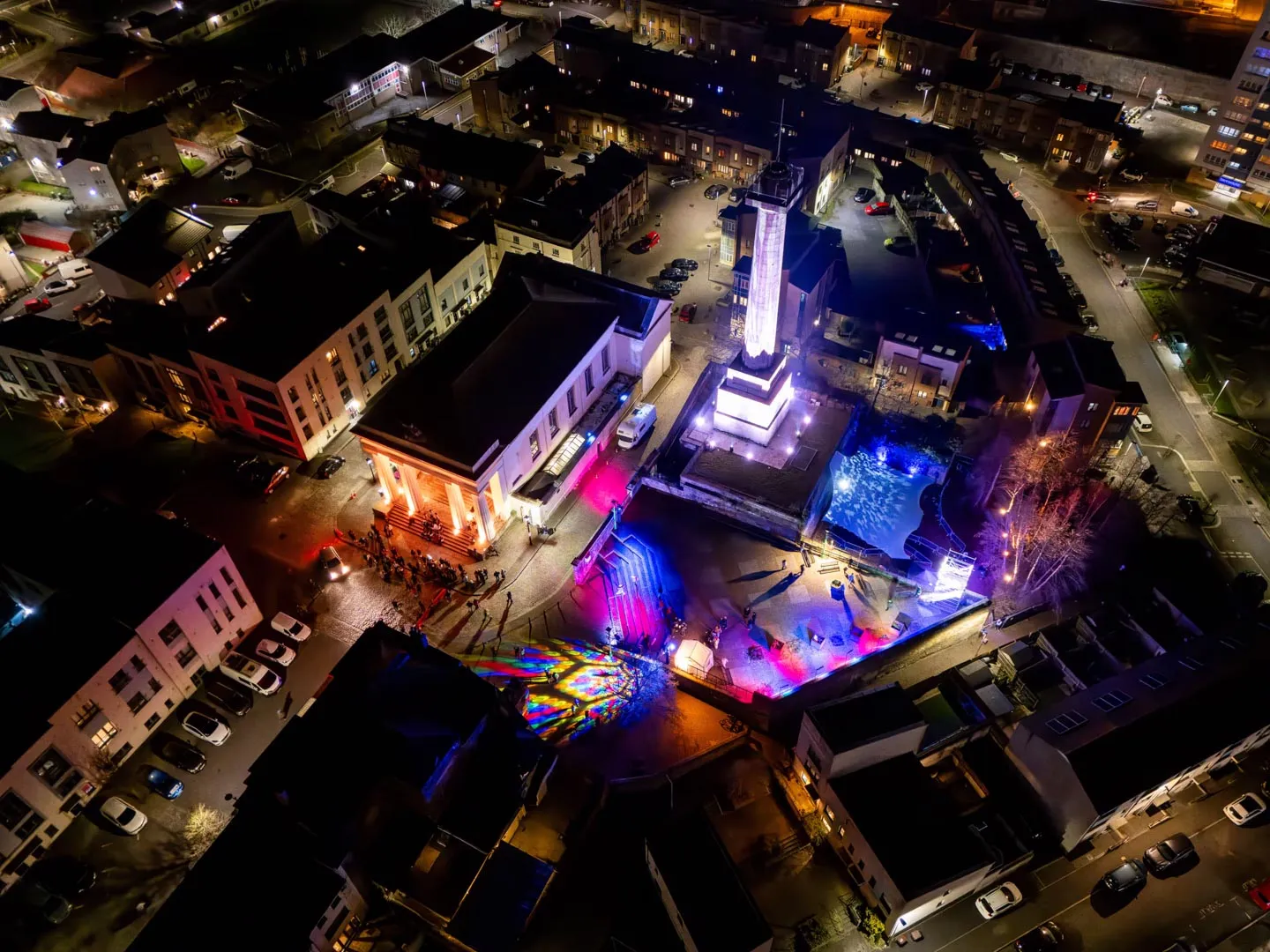 Aerial nighttime view of creative district with illuminated buildings and colourful light installations