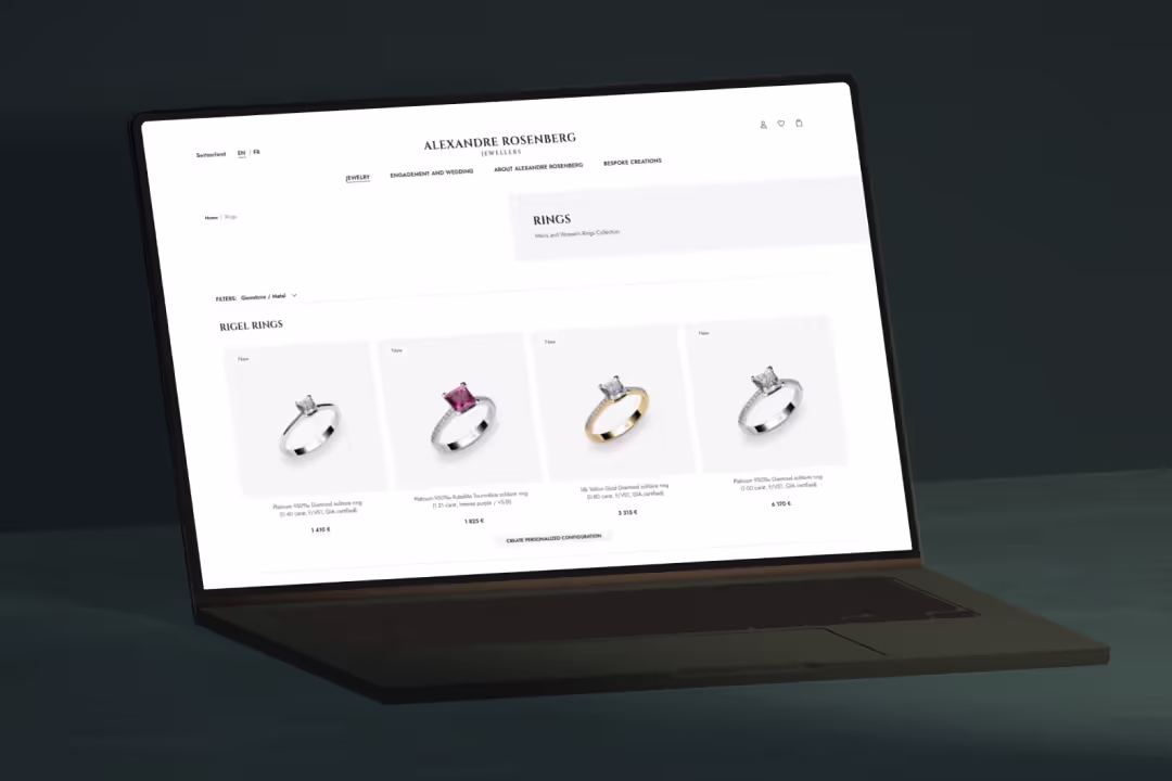 Laptop zeigt eine Schmuck-Website mit einer Auswahl von vier eleganten Ringen aus Platin und Gelbgold.
