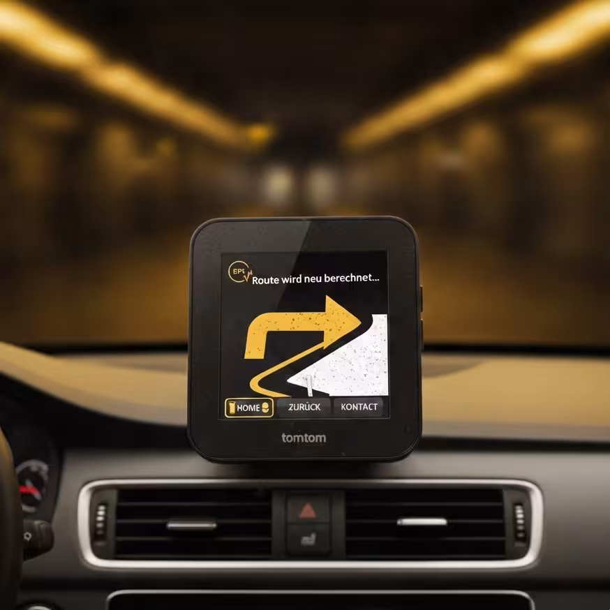 TomTom navigation device shows a recalculated route with a yellow arrow pointing right in a car.