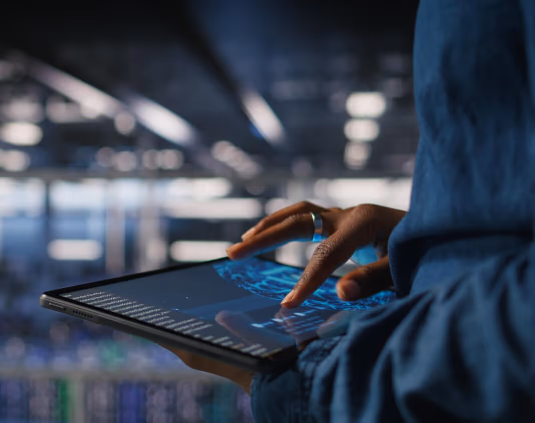 Person tippt auf einem Tablet mit Code und einem digitalen Globus im unscharfen Hintergrund.