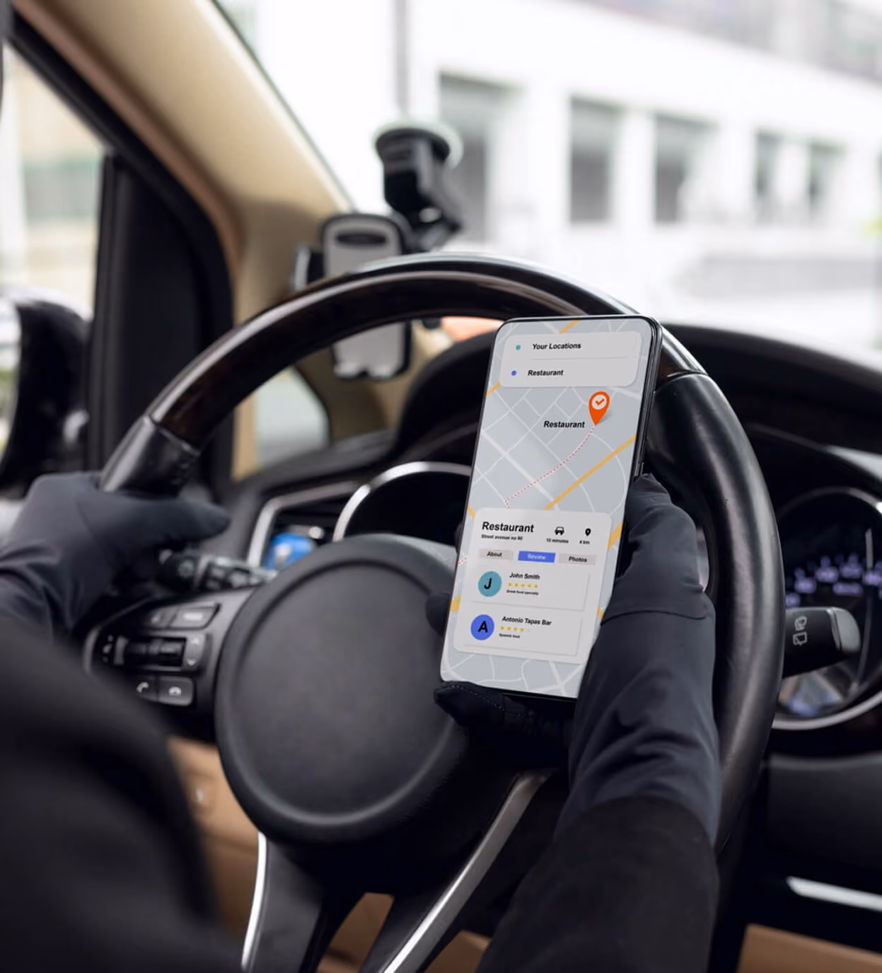 Fahrer mit Handschuhen hält Handy mit Navigations-App zum Restaurant im Auto.