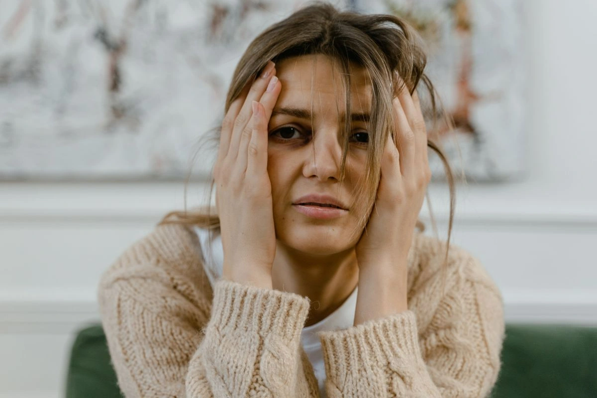 Photo of a traumatised woman with disheveled hair holding her face