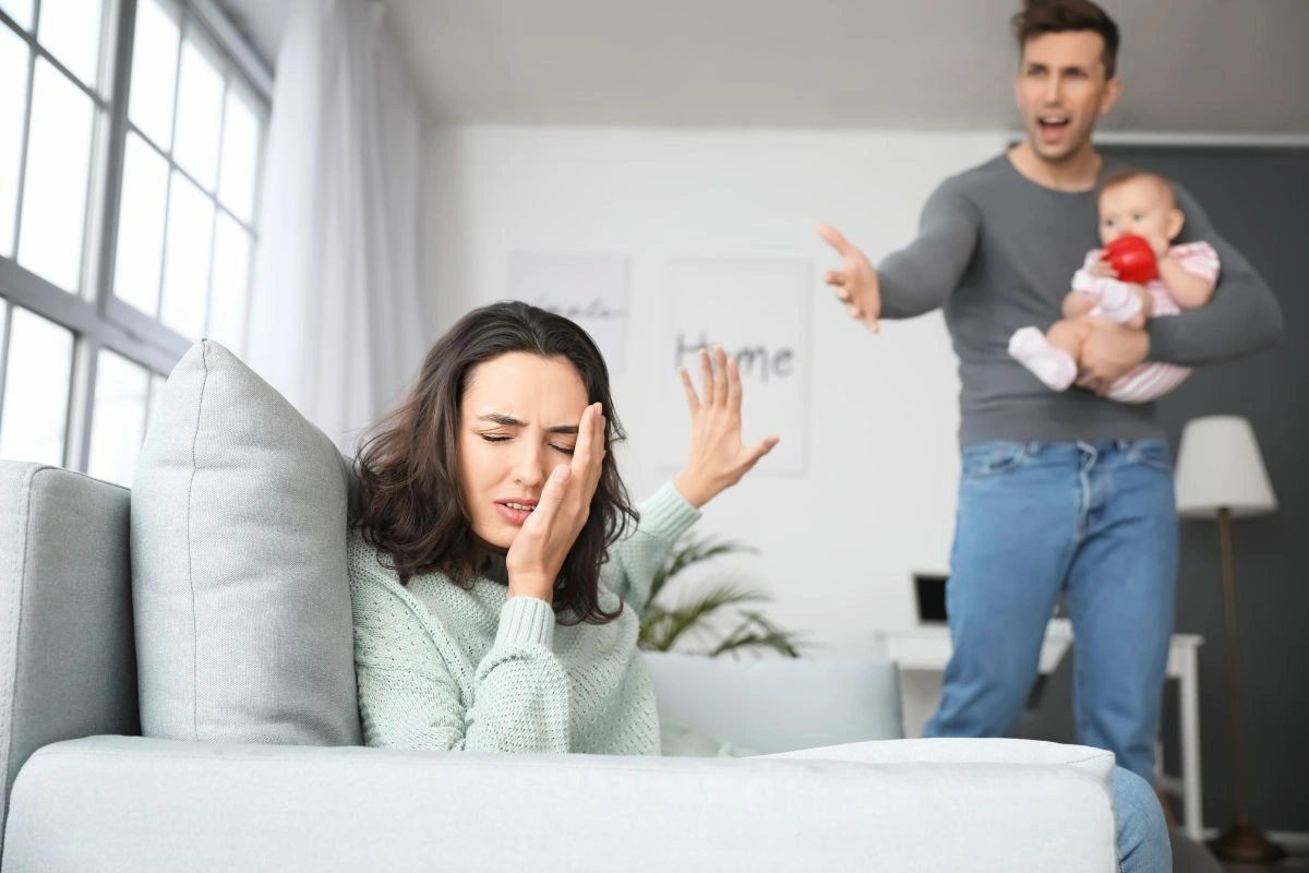 Photo of a woman having an argument with her husband who is holding a baby