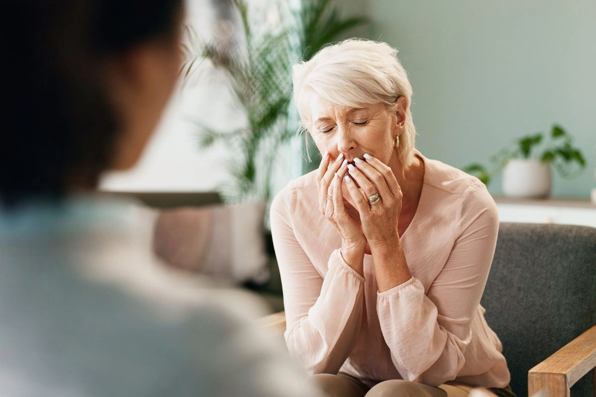 A woman covering her mouth with her hands during a counselling session
