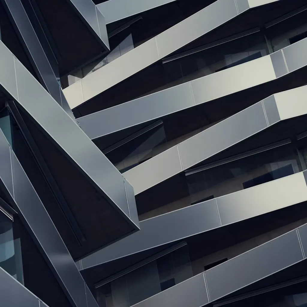Close-up of a modern building facade showing intersecting angled metal beams and glass panels.