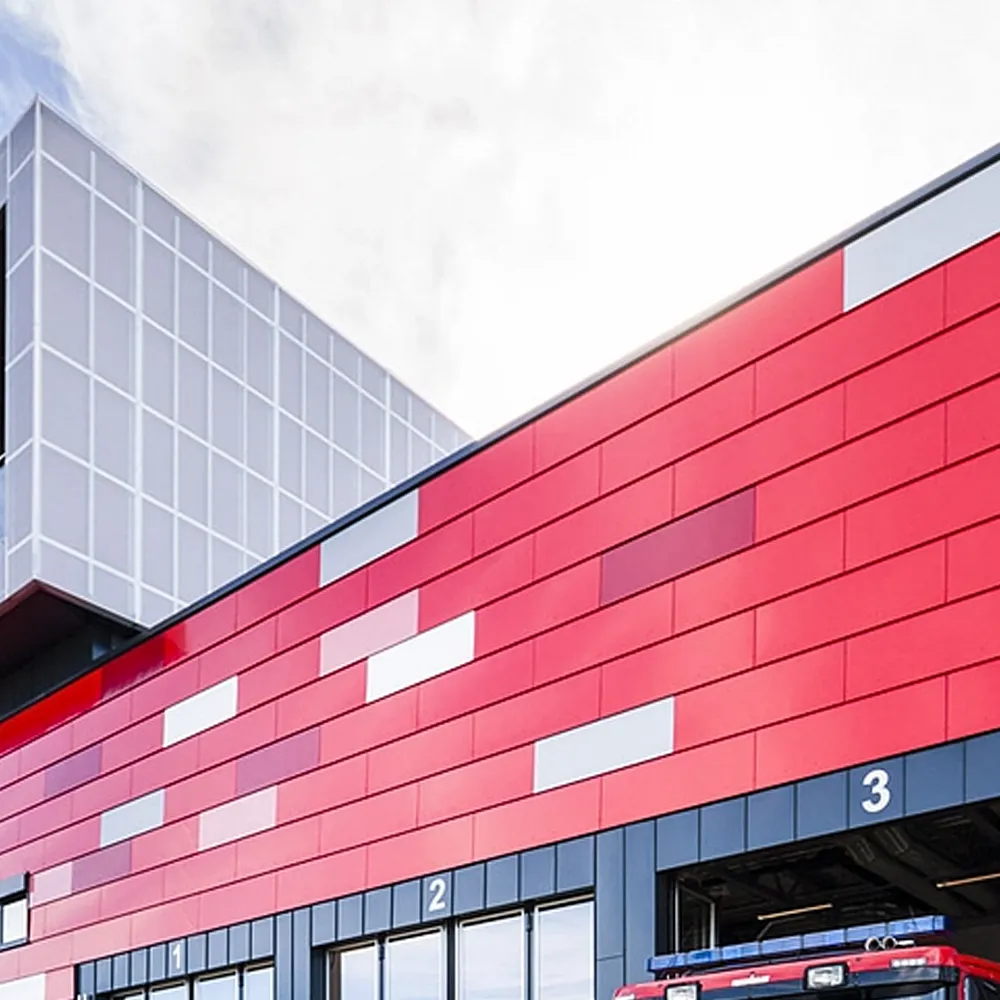 Modern building with red and gray panel facade featuring numbered garage doors, and a fire truck partially visible inside door number 3.