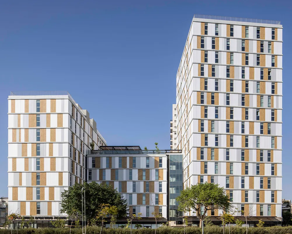 Modern multi-story residential building with white and wooden panel facade under clear blue sky.