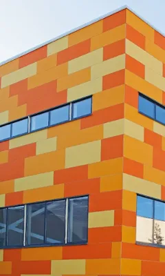 Modern building corner with orange, yellow, and red rectangular panels and horizontal dark blue windows.