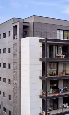 Side view of a modern apartment building with balconies and outdoor furniture.