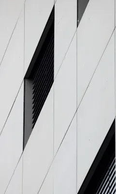 Close-up of a modern building facade with white panels and black window louvers.