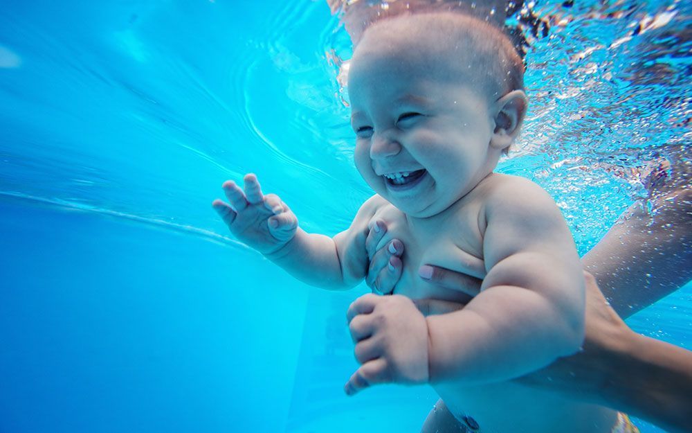 Glückliches Baby beim Babyschwimmen unter Wasser