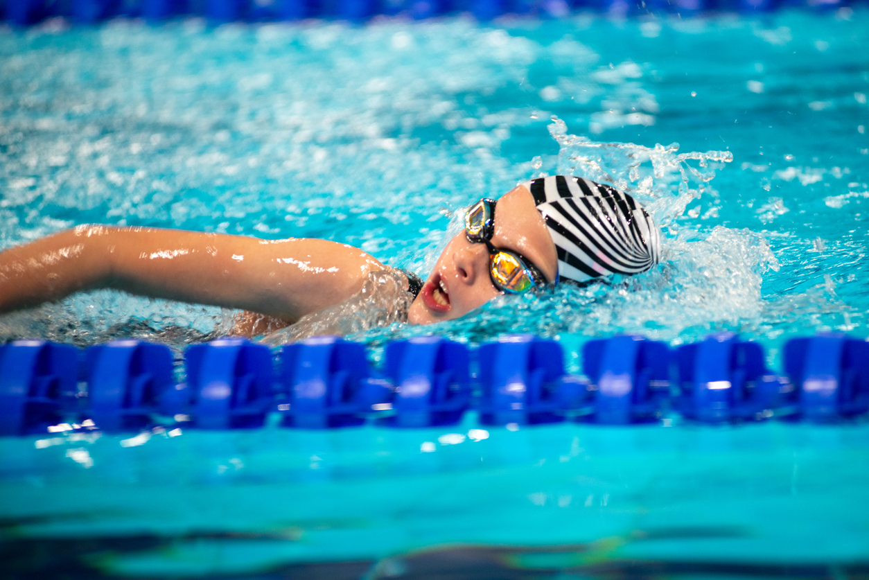 Kind beim Schwimmtraining im Becken, mit Schwimmbrille und Kraultechnik