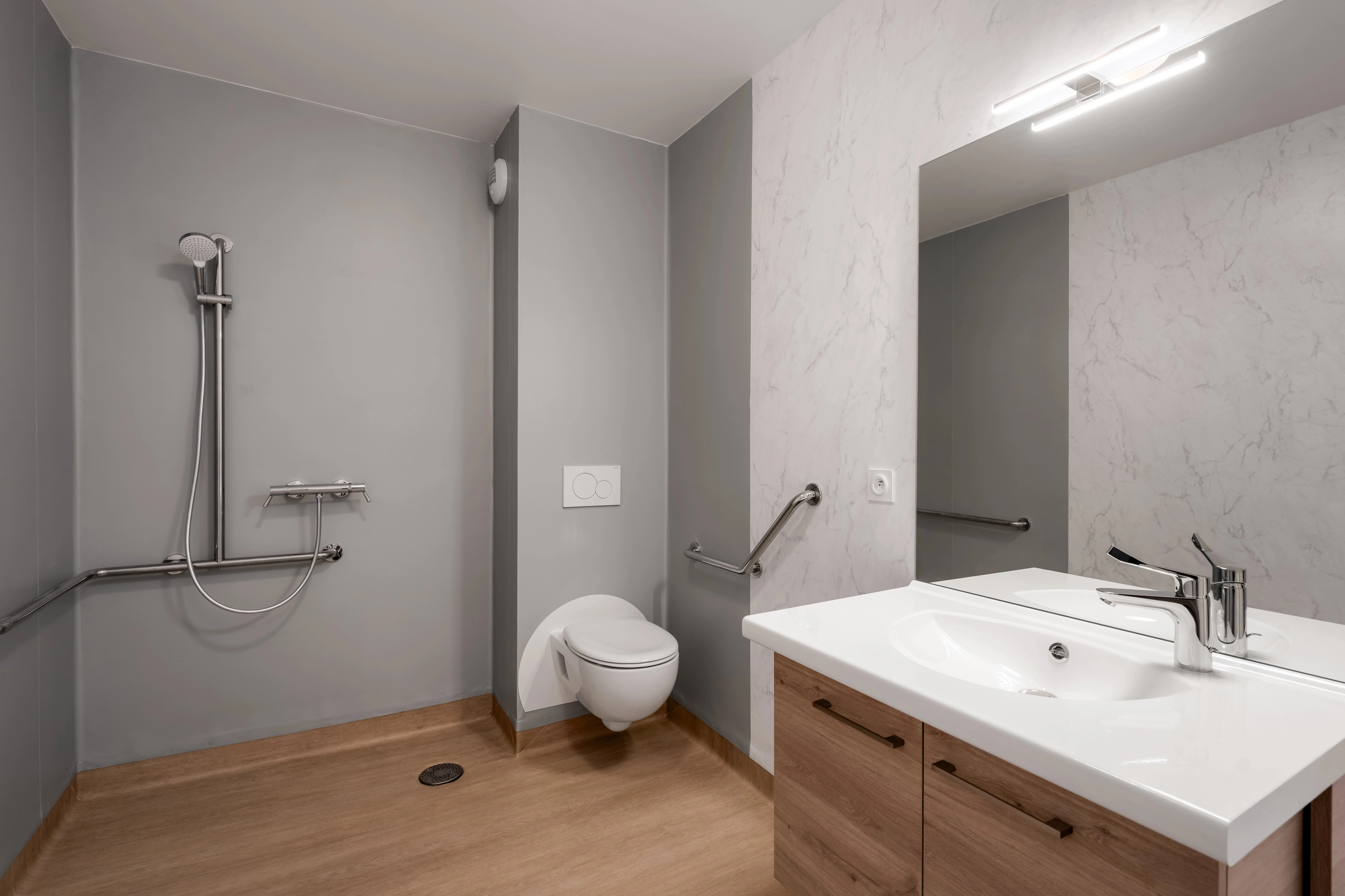 Salle d'eau adaptée avec douche à l'italienne sans seuil et barres de maintien