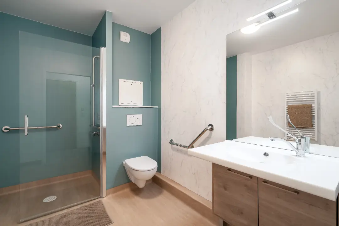 Salle d'eau adaptée avec douche à l'italienne sans seuil et barres de maintien