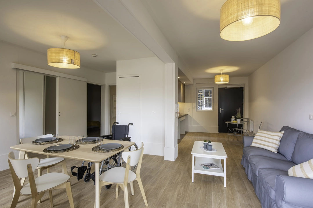 Une personne en fauteuil roulant dans la chambre de son appartement Mobicap.