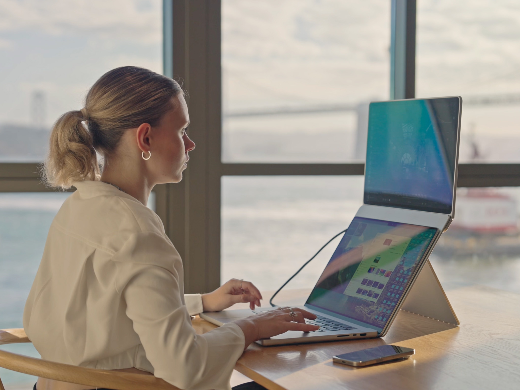 Person working on a laptop with Standout portable monitor, improving posture at a cabin.