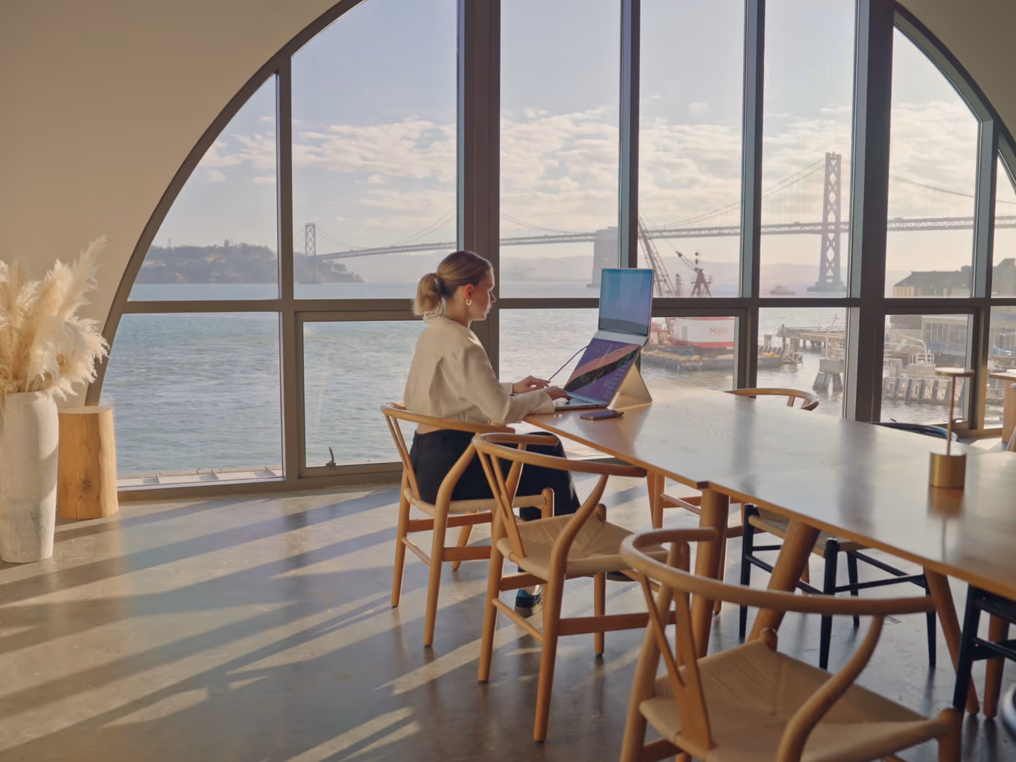 Person working remotely with MacBook Pro and Standout portable monitor in Shack15, showcasing ergonomic posture and dual-screen setup.