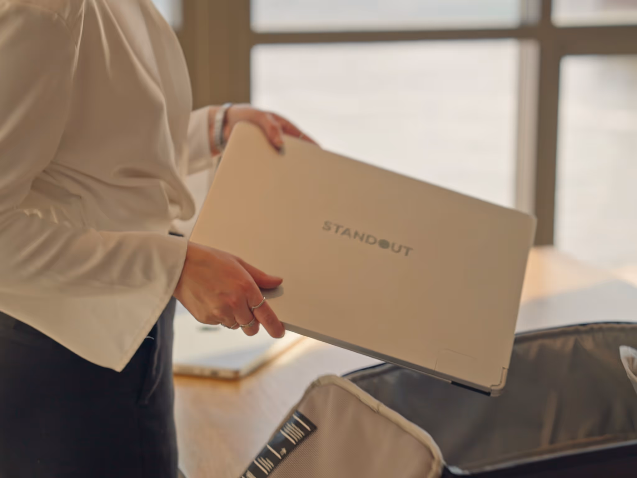 “Closed Standout aluminum portable monitor on a desk beside camera and smartphone.