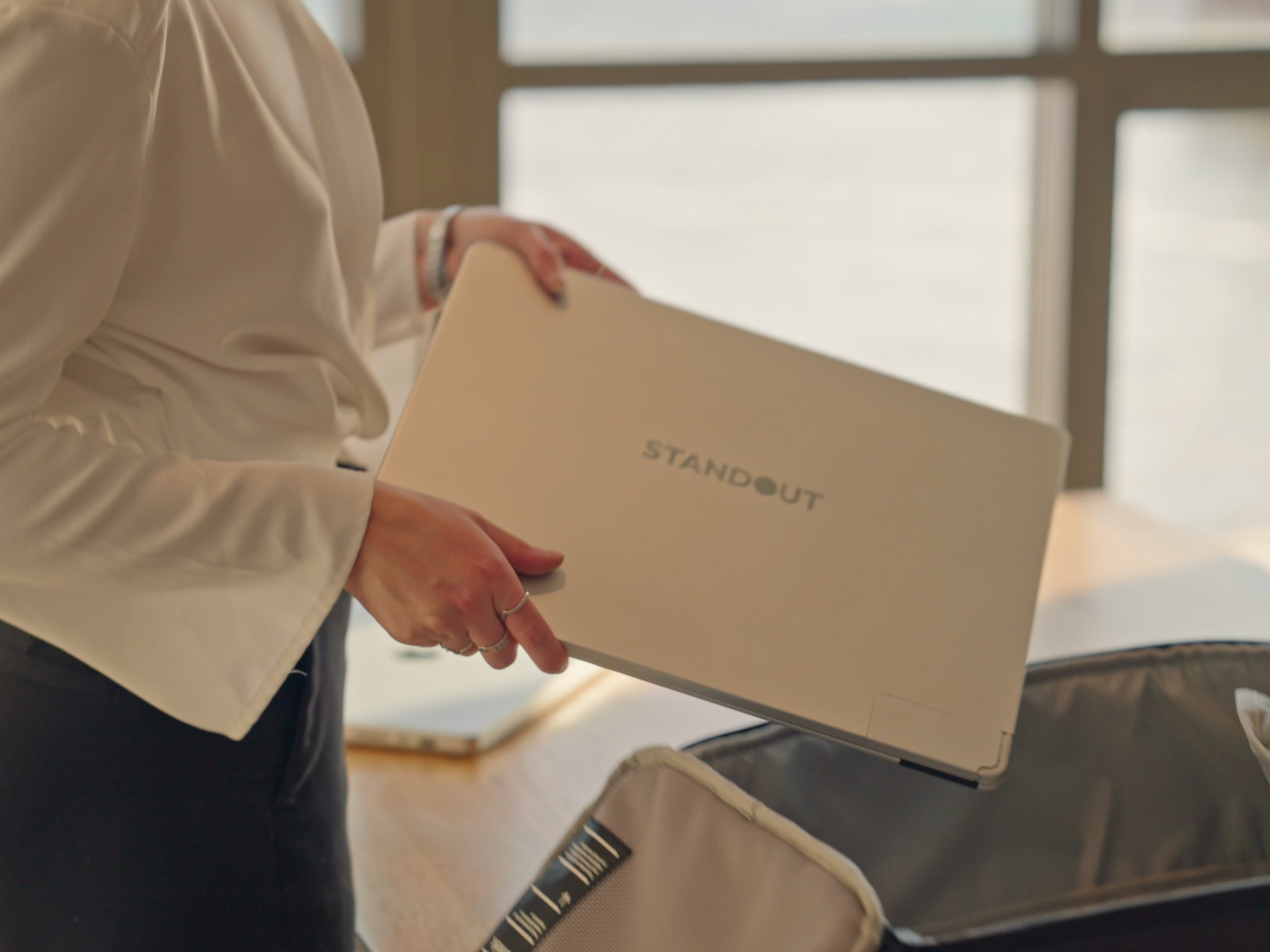 “Closed Standout aluminum portable monitor on a desk beside camera and smartphone.